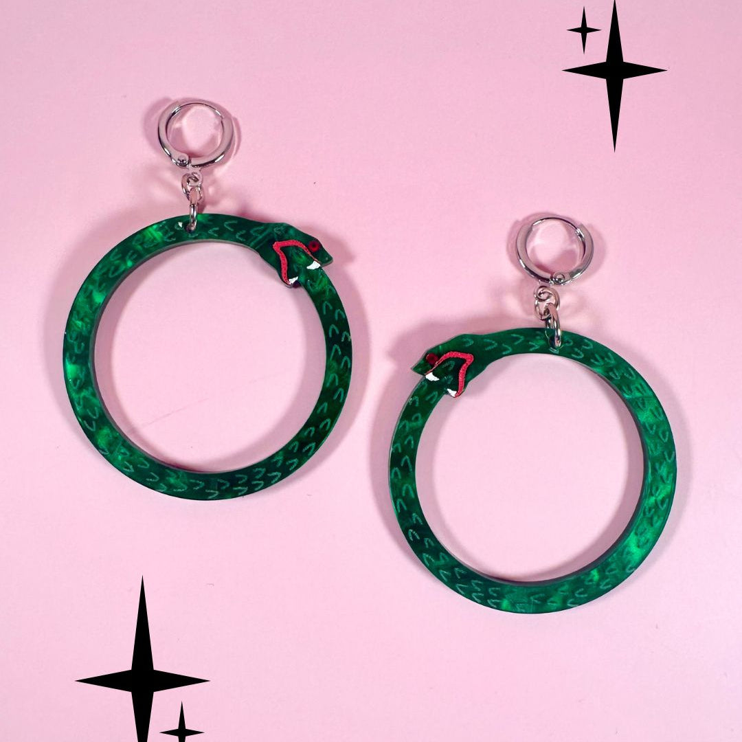 Green hoop earrings with a snake design on a pink background