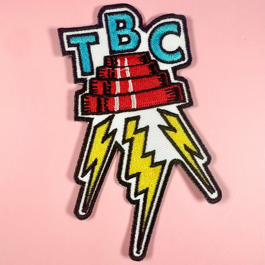 Patch with 'TBC' text and lightning bolts on a pink background
