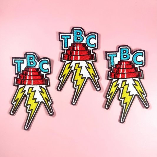 Three 'TBC' logo pins with lightning bolts on a pink background