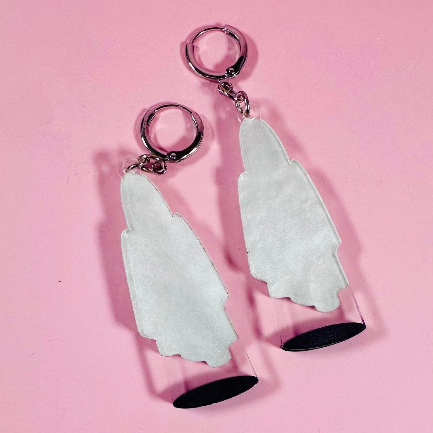 Pair of white arrowhead-shaped keychains on a pink background