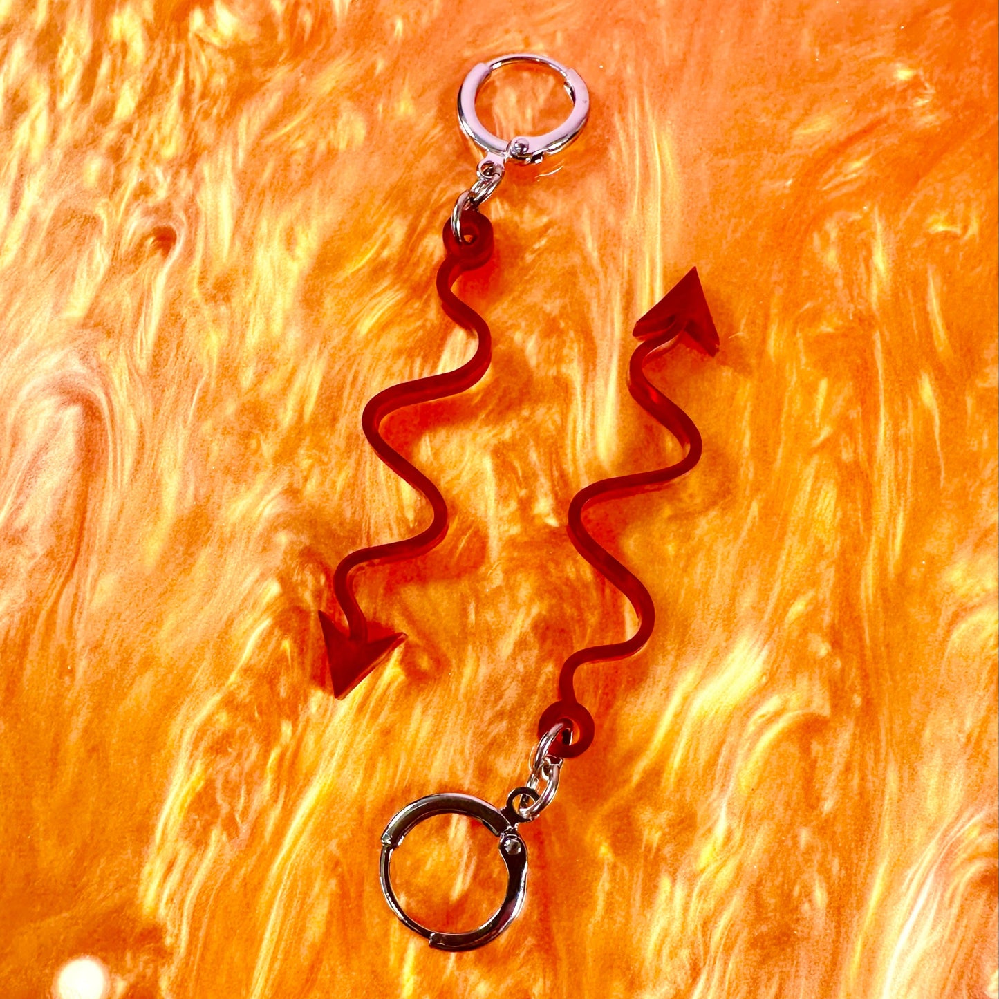 Pair of brown wavy earrings on a textured orange background