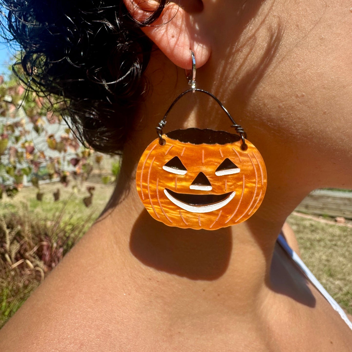 Person wearing a pumpkin-shaped earring with a blurred background