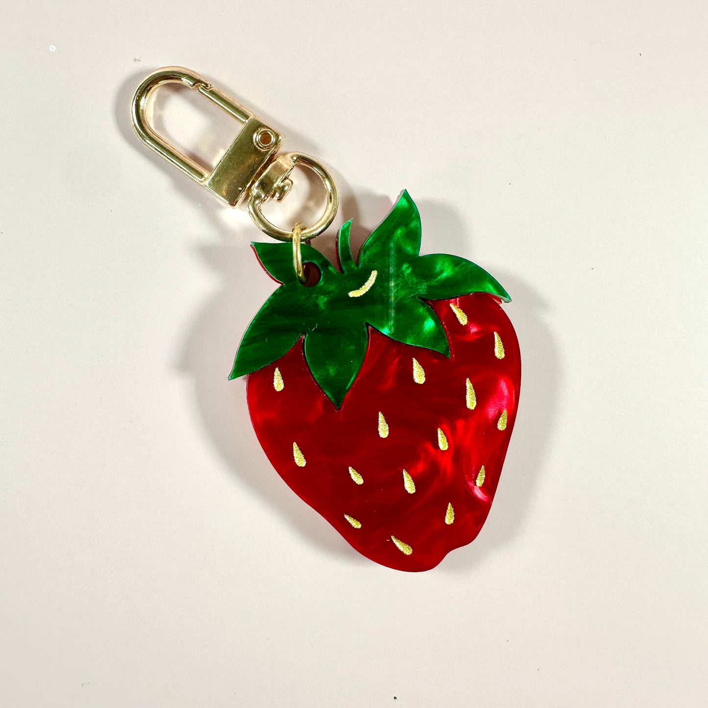 Strawberry-shaped keychain with a gold clasp on a white background