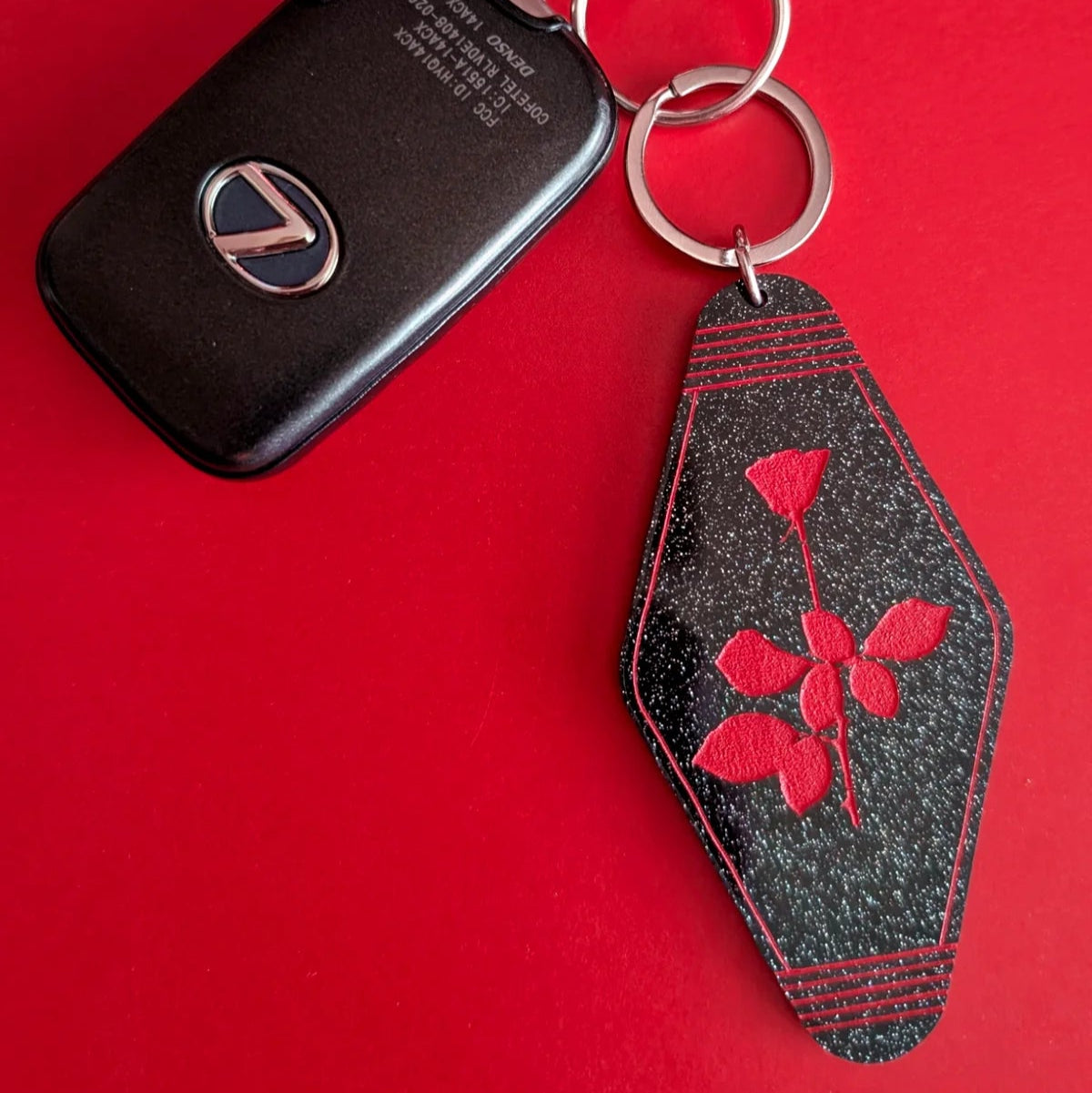 Keychain with a black tag and red floral design on a red background