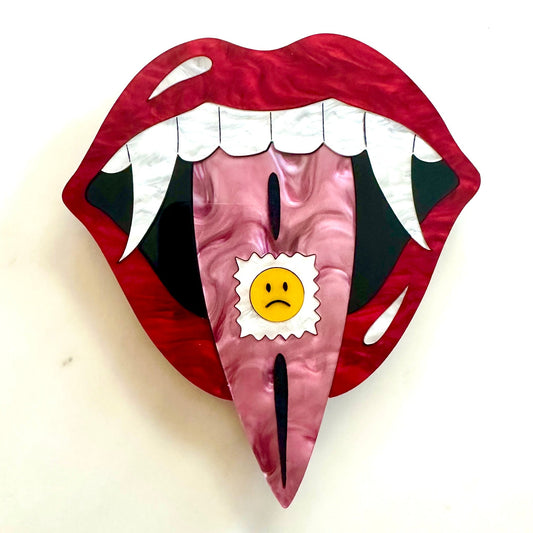 Red lips with fangs and a sad face emoji on a white background