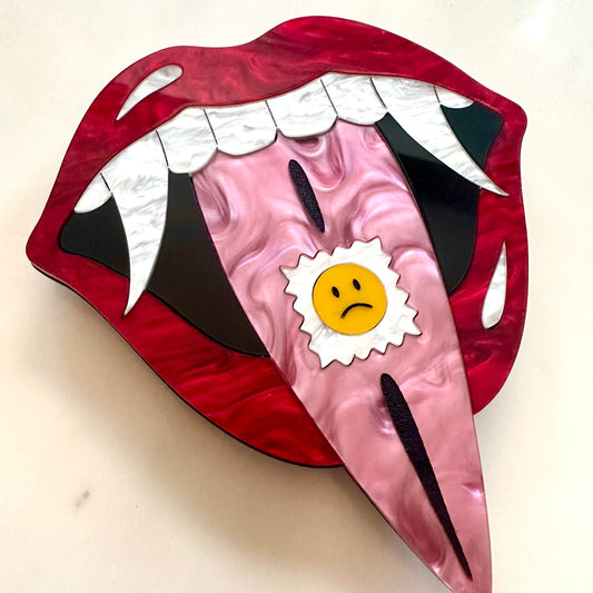 Cartoonish mouth design with a sad face sticker on a beige background
