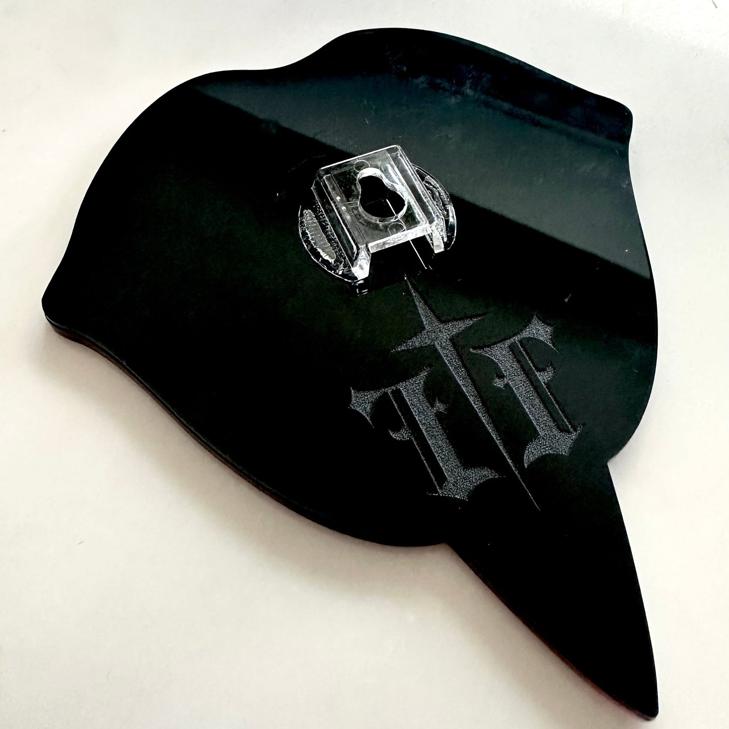 Black plastic component with a logo on a white background