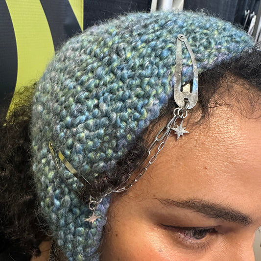Person wearing a textured blue headband with metal clips and chains.