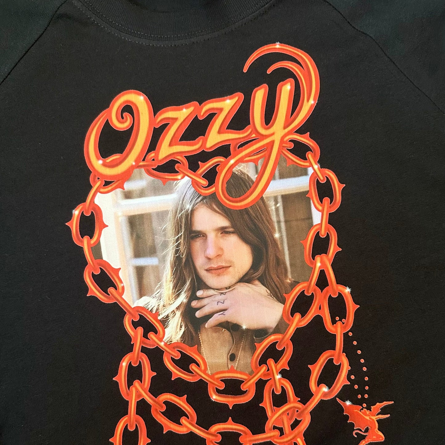 Black sweatshirt with orange 'Ozzy' design featuring a portrait of a person.