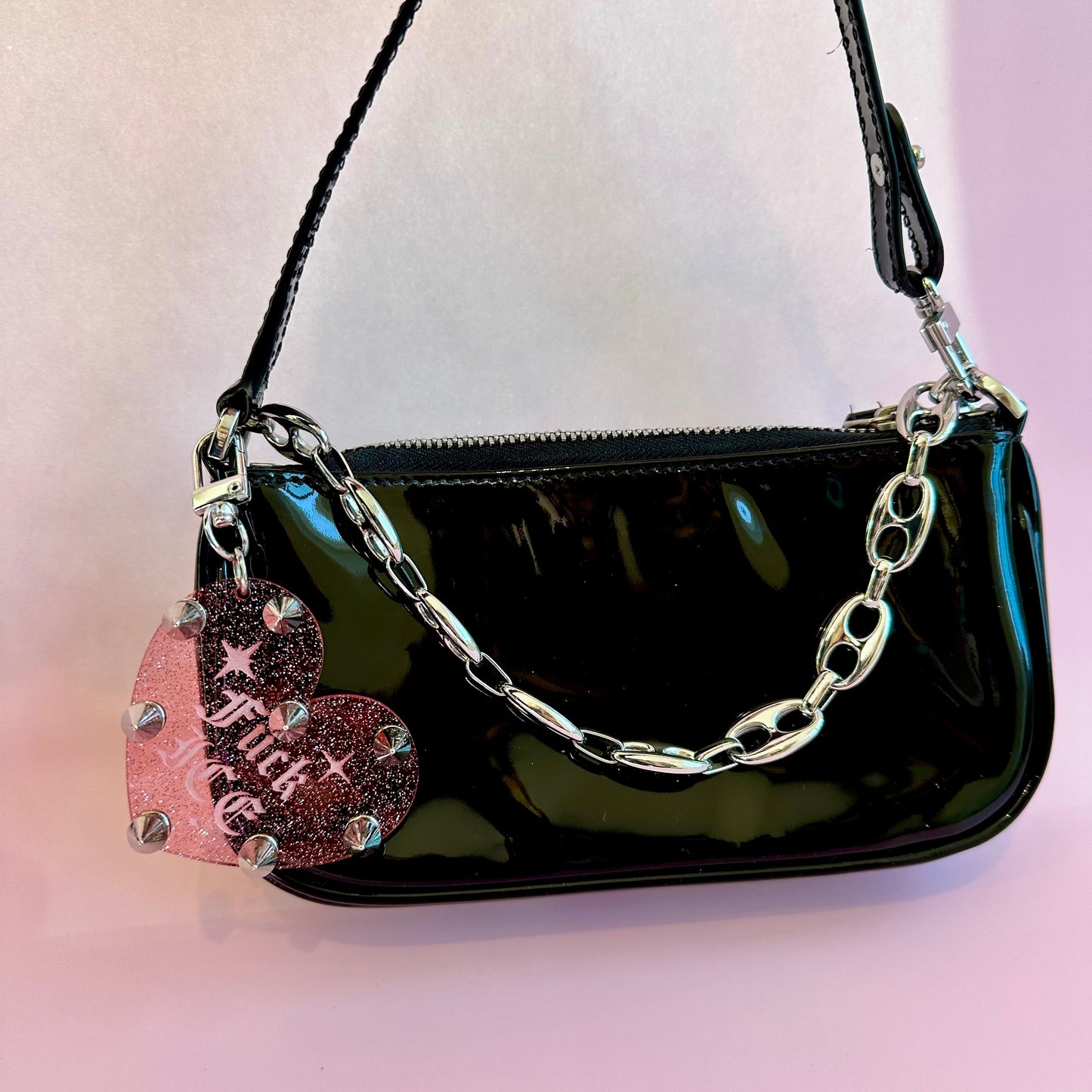 Black handbag with a chain handle on a light pink background