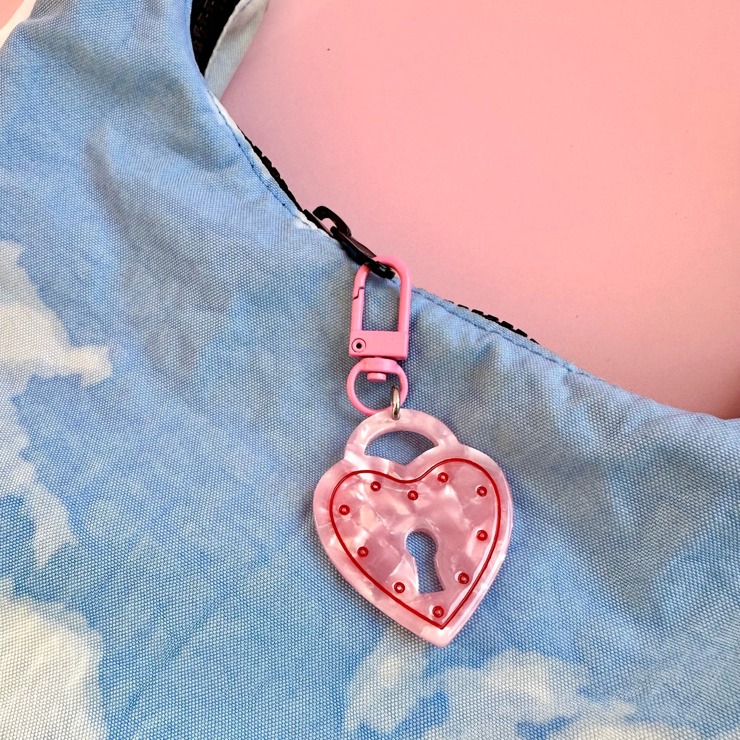 Pink heart-shaped keychain with a lock design on a blue denim background