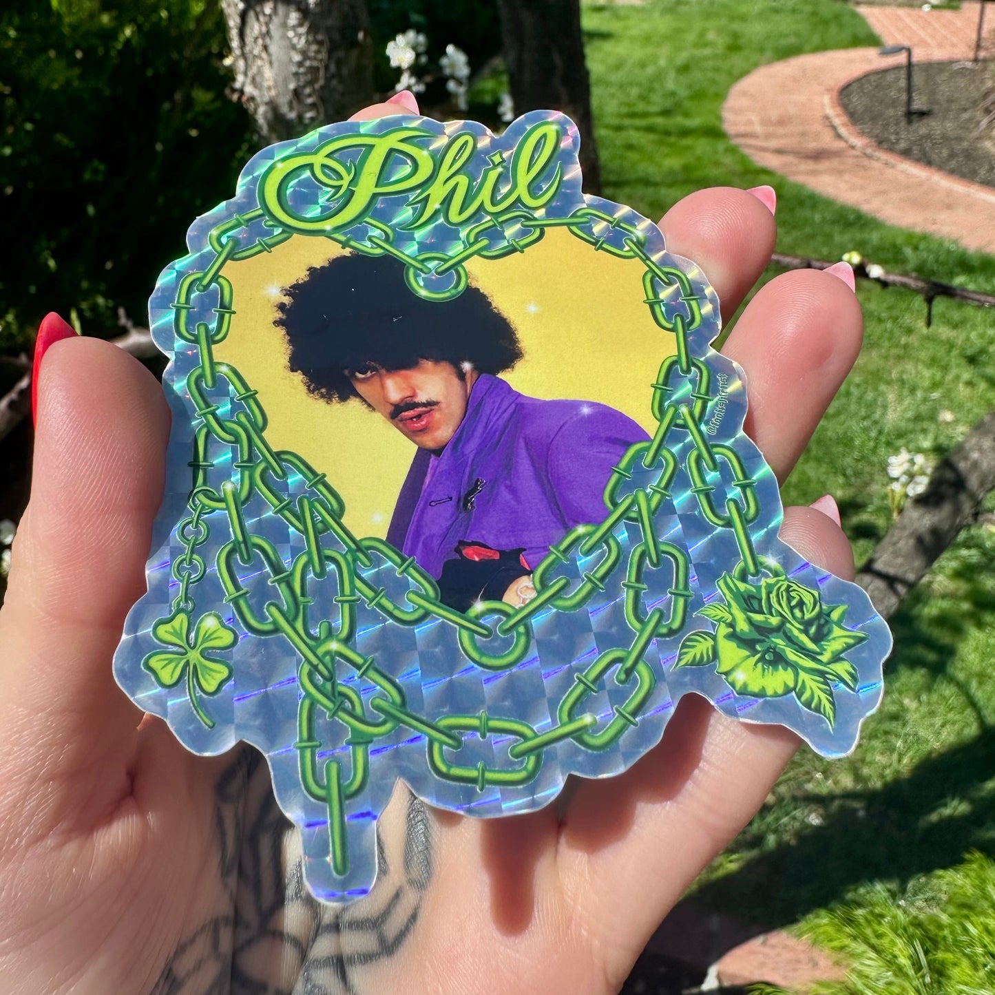 Sticker of a person with afro and mustache in a decorative frame held outdoors.