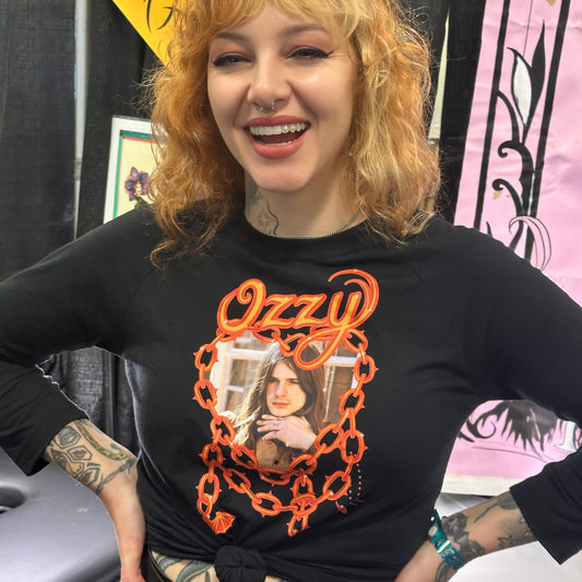 Person wearing a black t-shirt with 'Ozzy' design, standing in front of a colorful background.