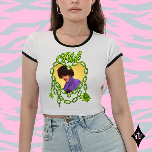 Person wearing a white t-shirt with a graphic design and text, standing against a pink and gray patterned background.