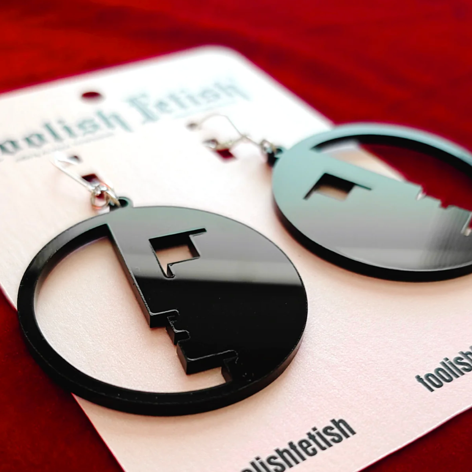 Black circular earrings on a 'foolishletish' branded card with a red background