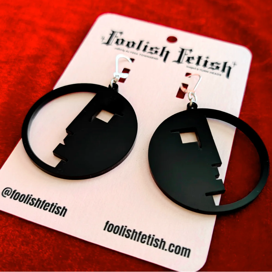 Black hoop earrings on a 'Foolish Felish' branded card against a red background