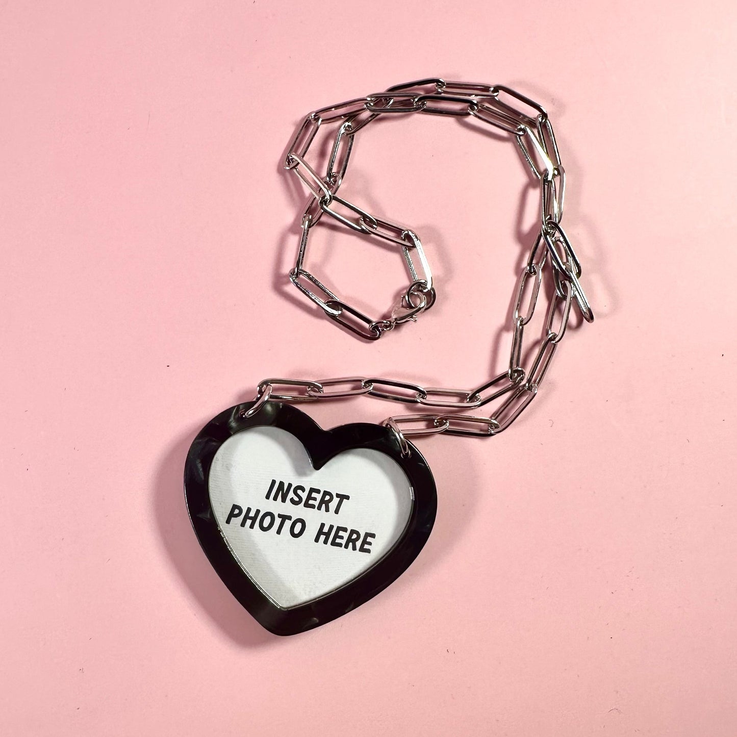 Heart-shaped photo frame charm on a pink background