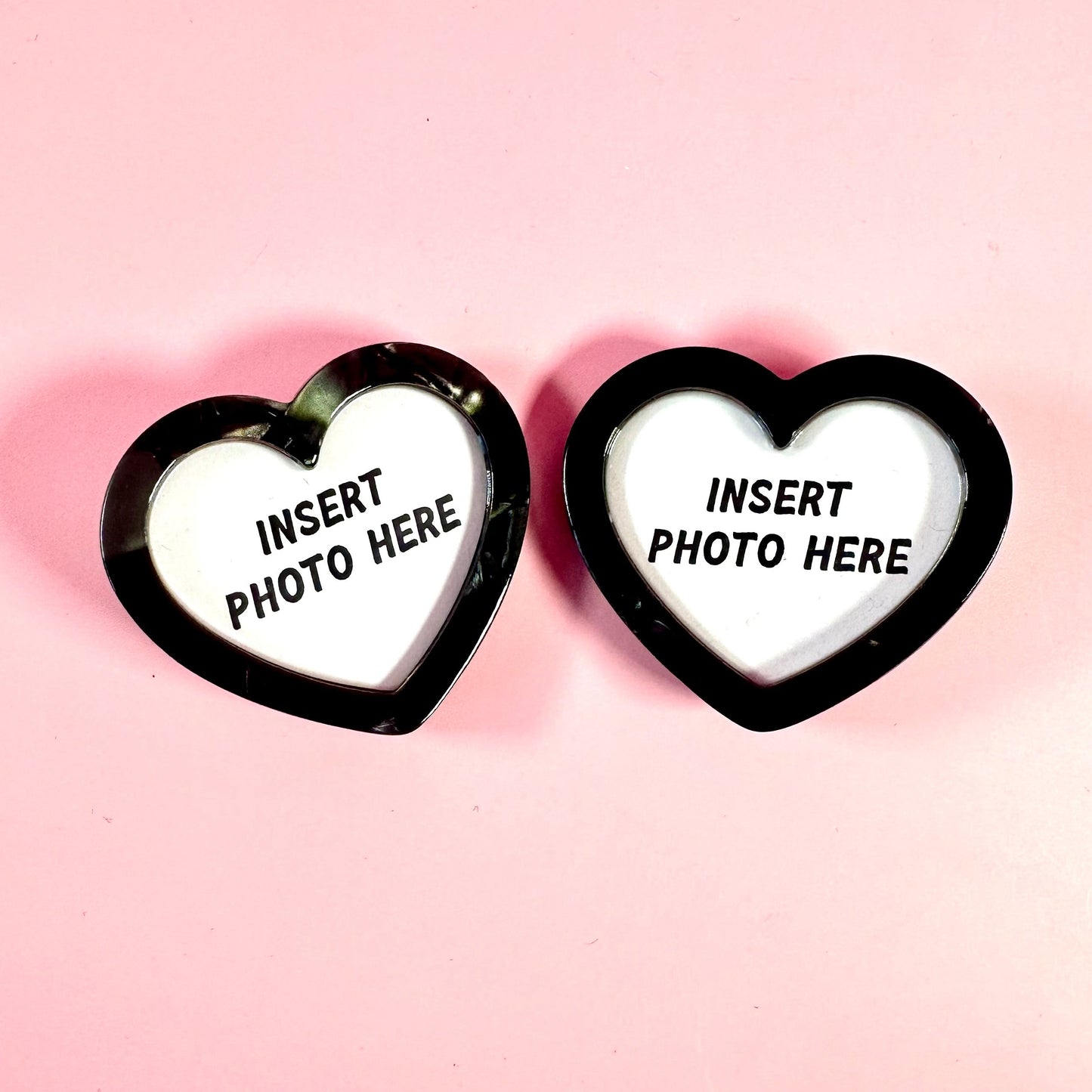 Two heart-shaped photo frames with 'Insert Photo Here' text on a pink background