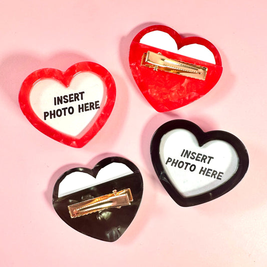 Heart-shaped photo frames with clips on a pink background
