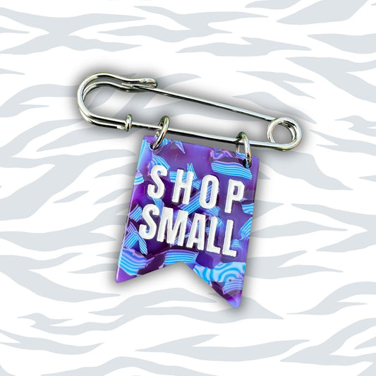 safety pin with 'Shop Small' banner on a wavy white background