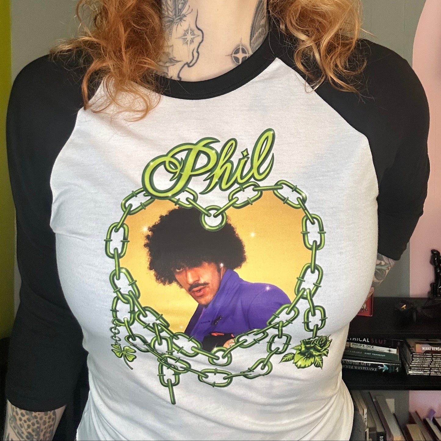 Person wearing a t-shirt with a graphic design of a person with curly hair and the name 'Phil'.
