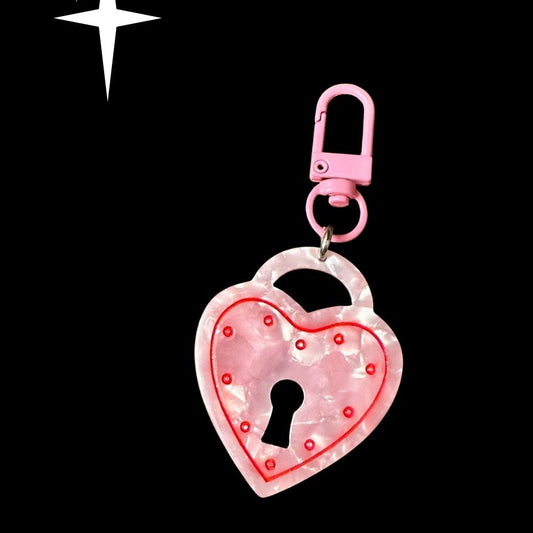Heart-shaped lock keychain with pink glitter on a black background