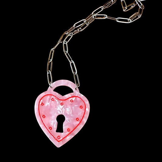 Pink heart-shaped lock pendant on a chain against a black background