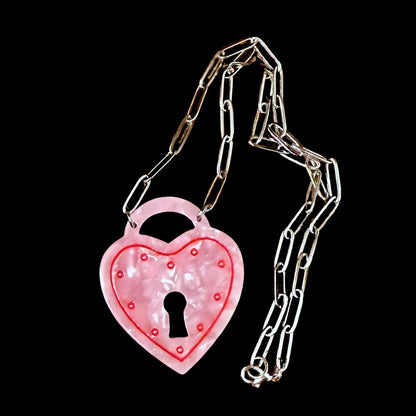 Pink heart-shaped padlock with chain on a black background