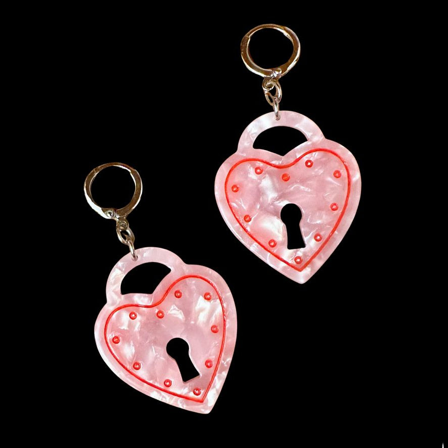 Two heart-shaped lock keychains with a keyhole design on a black background.