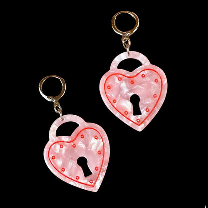 Two heart-shaped lock keychains with a keyhole design on a black background.