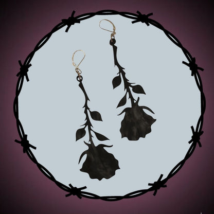 Black rose earrings on a circular background with barbed wire, featuring a logo in the corner.