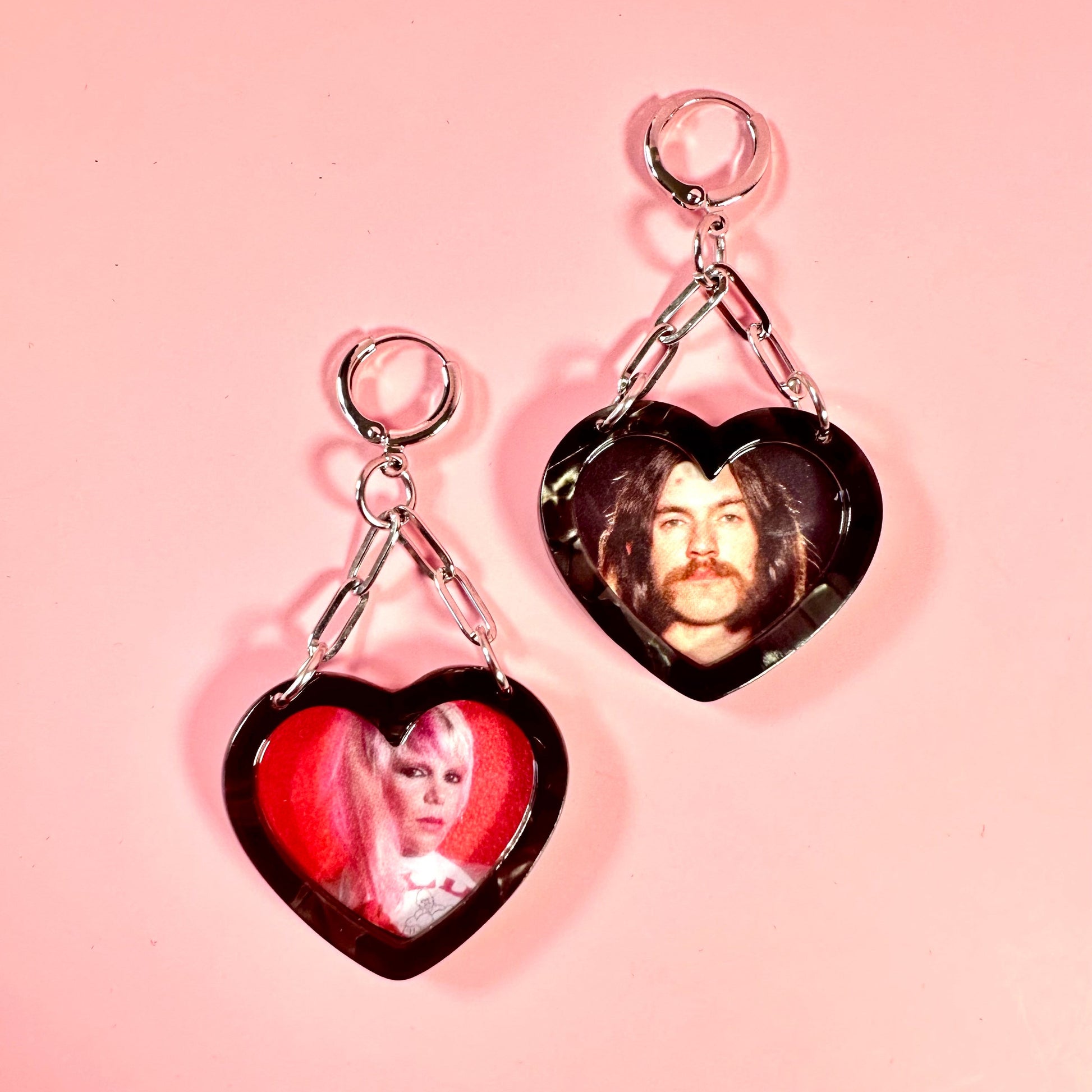Heart-shaped earrings with images of a man and a woman on a pink background