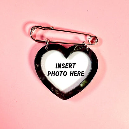 Heart-shaped photo frame with a safety pin on a pink background