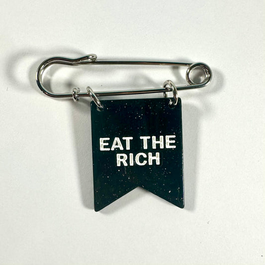 Pin with 'Eat the Rich' text on a black background