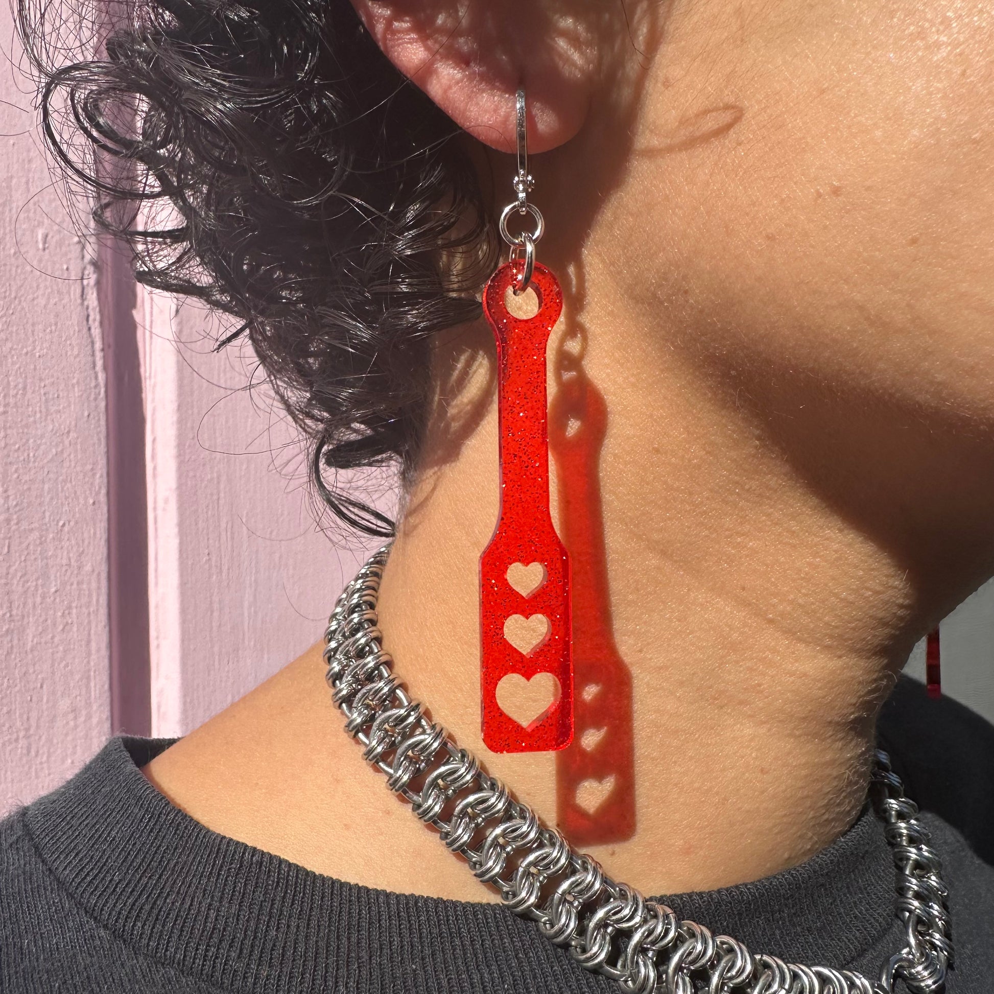 Person wearing a red heart-shaped earring with a blurred background