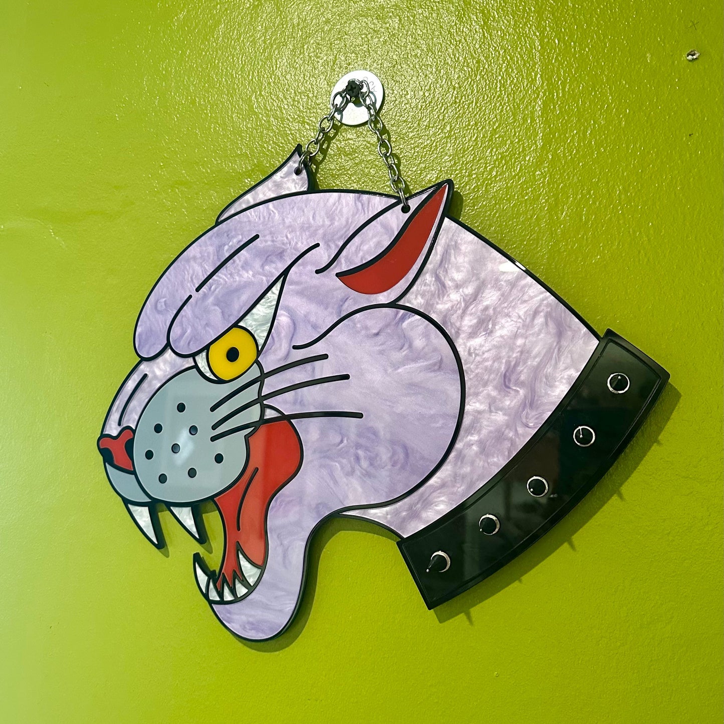 Decorative wall hanging with a cartoonish cat design on a green background