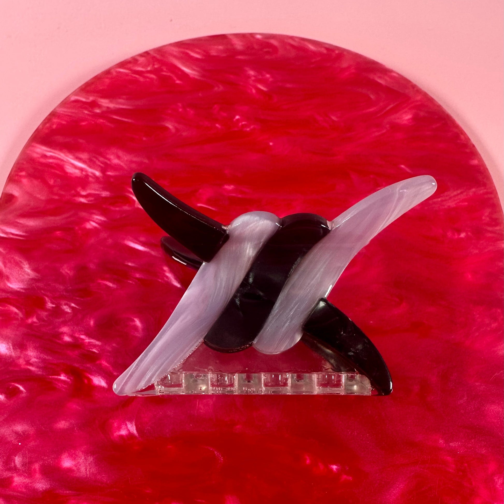 Black and white hair clip on a pink textured background