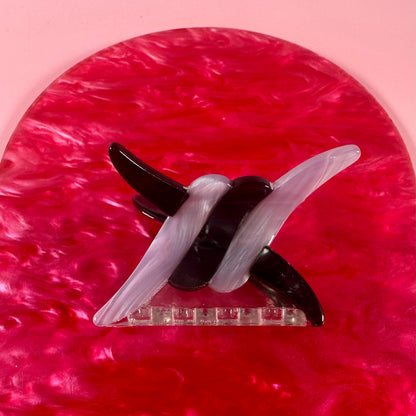 Black and white hair clip on a pink textured background