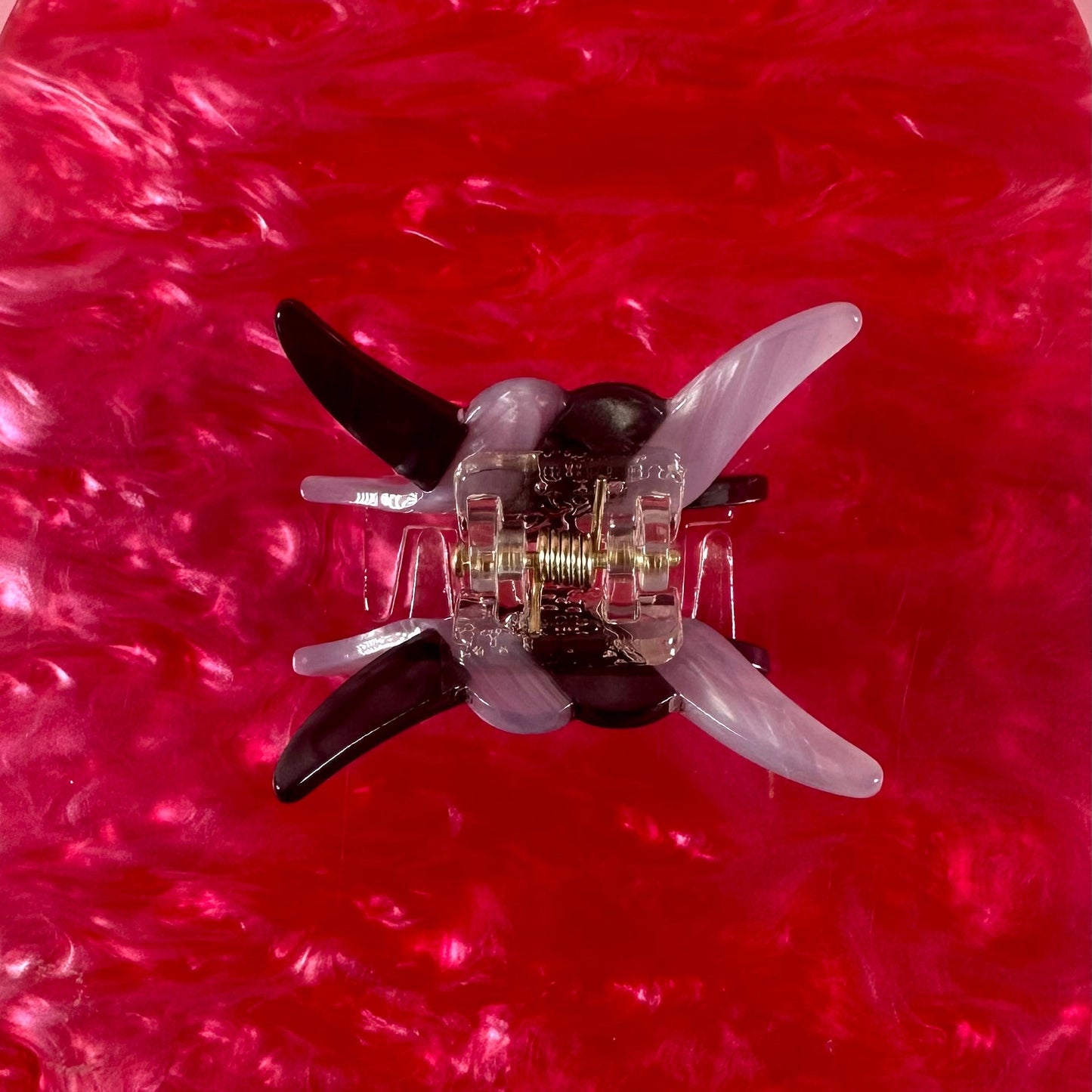 Small transparent object with black and white components on a red textured background