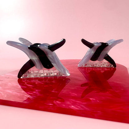 Two black and clear glass sculptures on a red platform with a pink gradient background