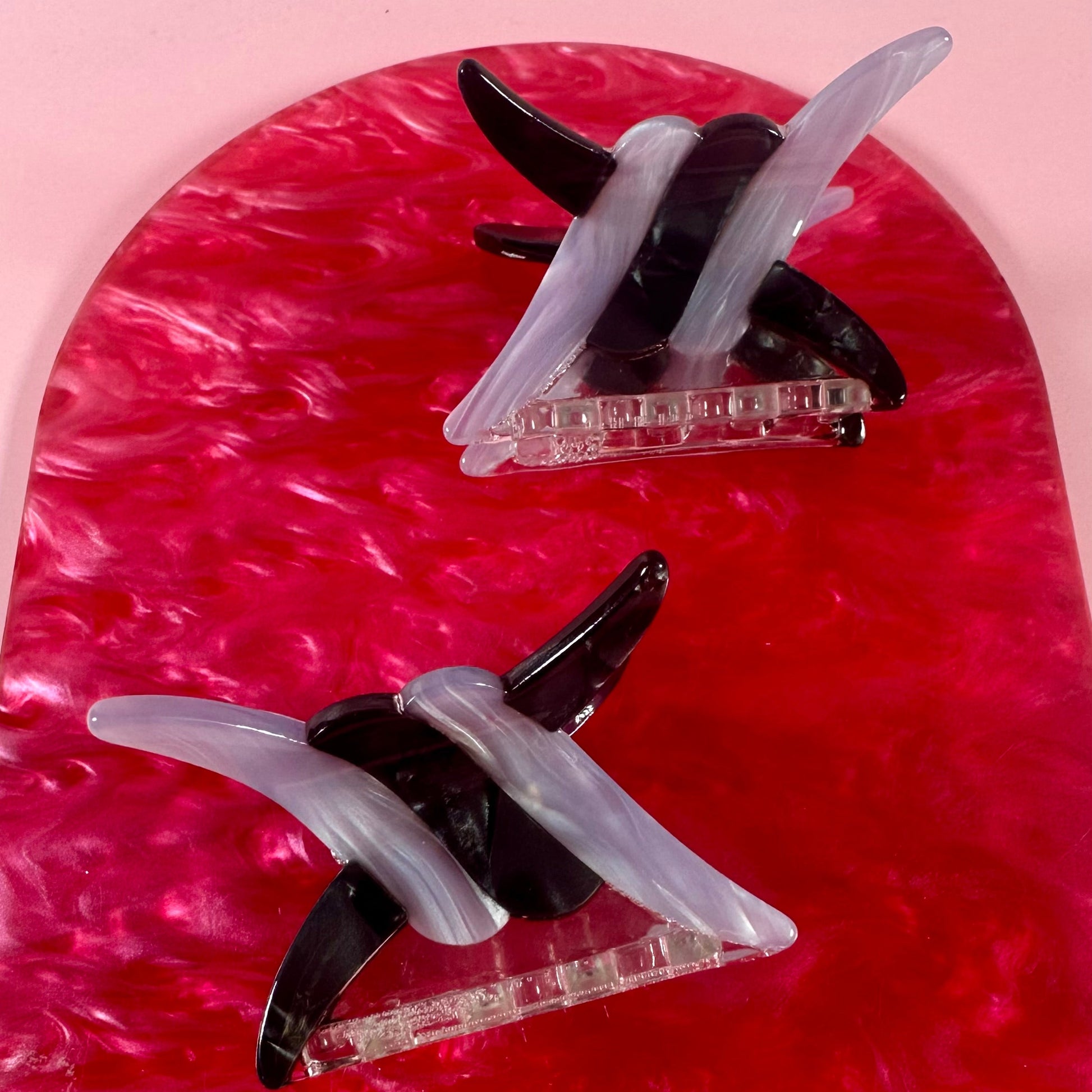 Two hair clips on a red and pink marbled background