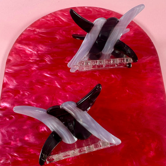 Two hair clips on a red and pink marbled background