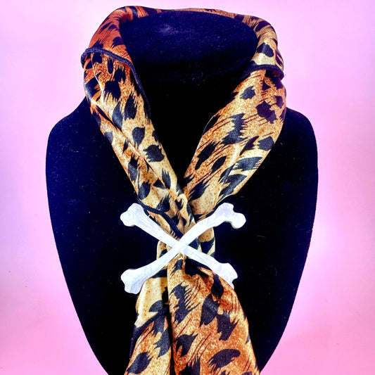 Leopard print scarf with bone-shaped clips on a black mannequin against a pink background