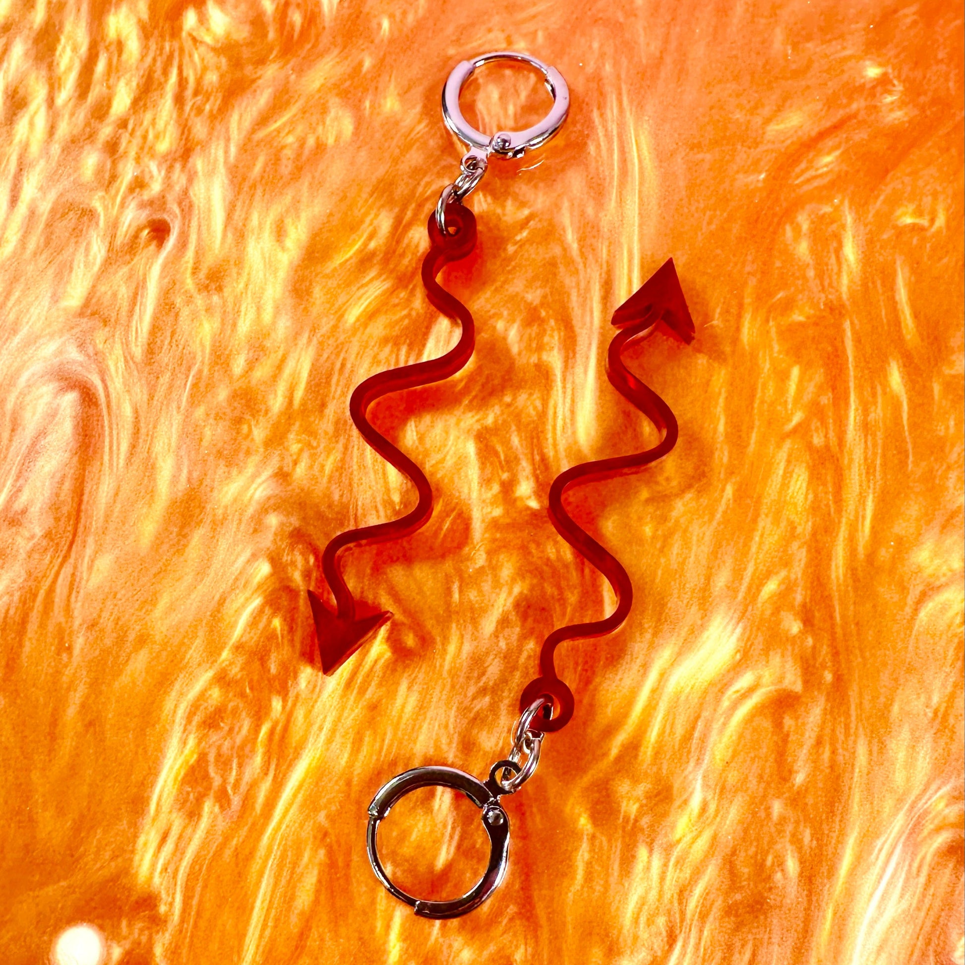 Pair of brown wavy earrings on a textured orange background