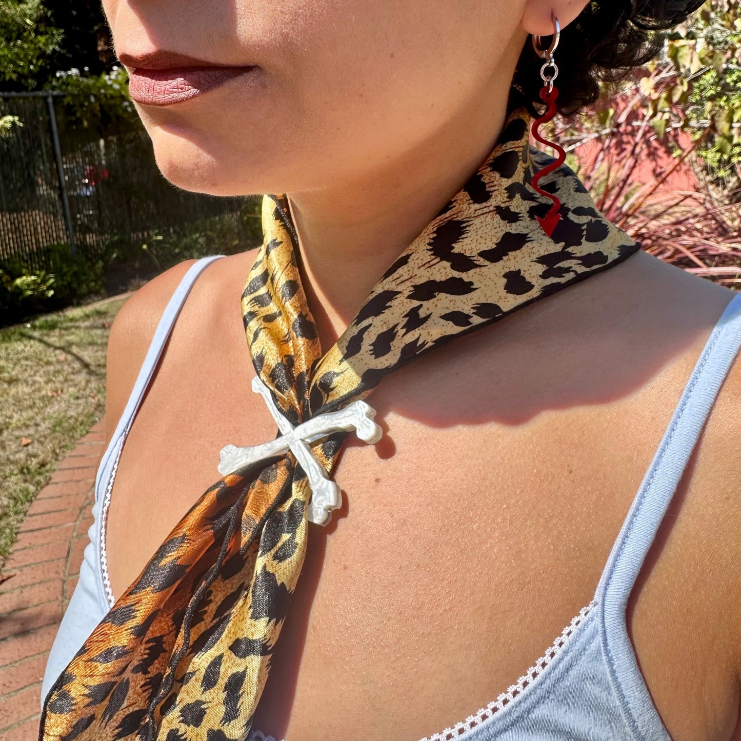 Woman wearing a leopard print scarf around her neck with a blurred outdoor background