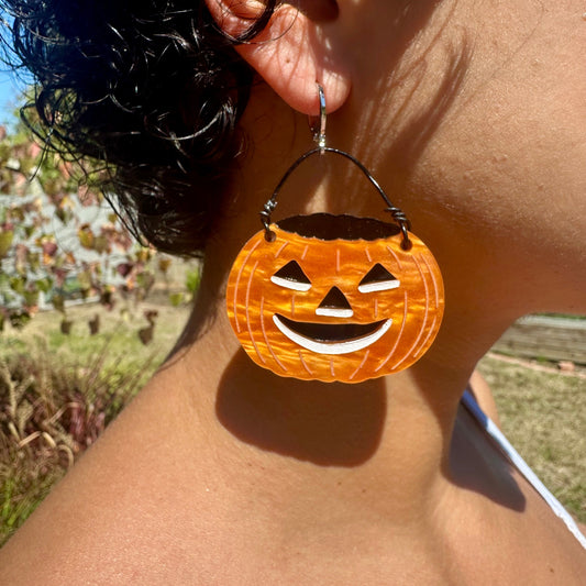 Person wearing a pumpkin-shaped earring with a blurred background