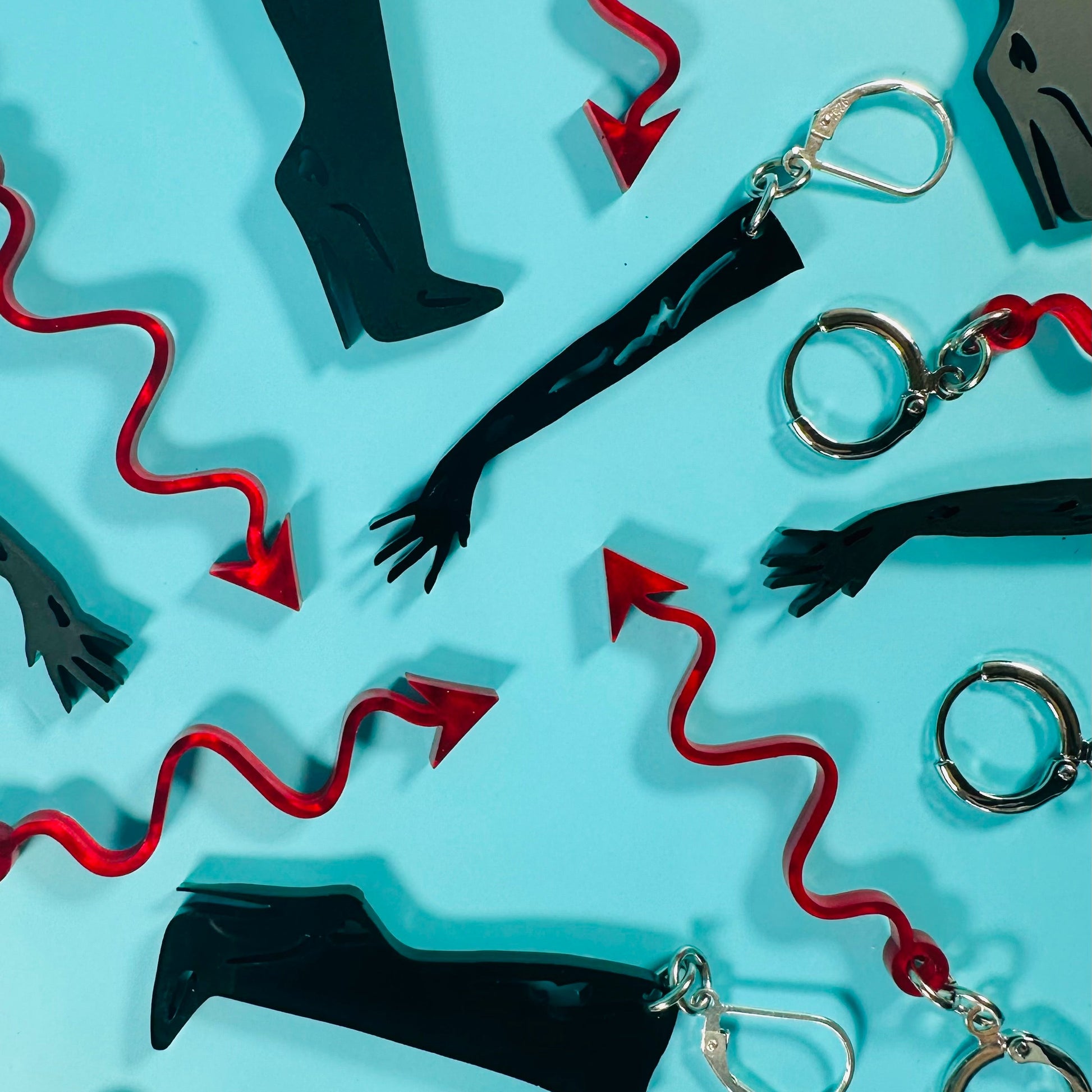 Keychains with black boots, red whips, and silver handcuffs on a light blue background
