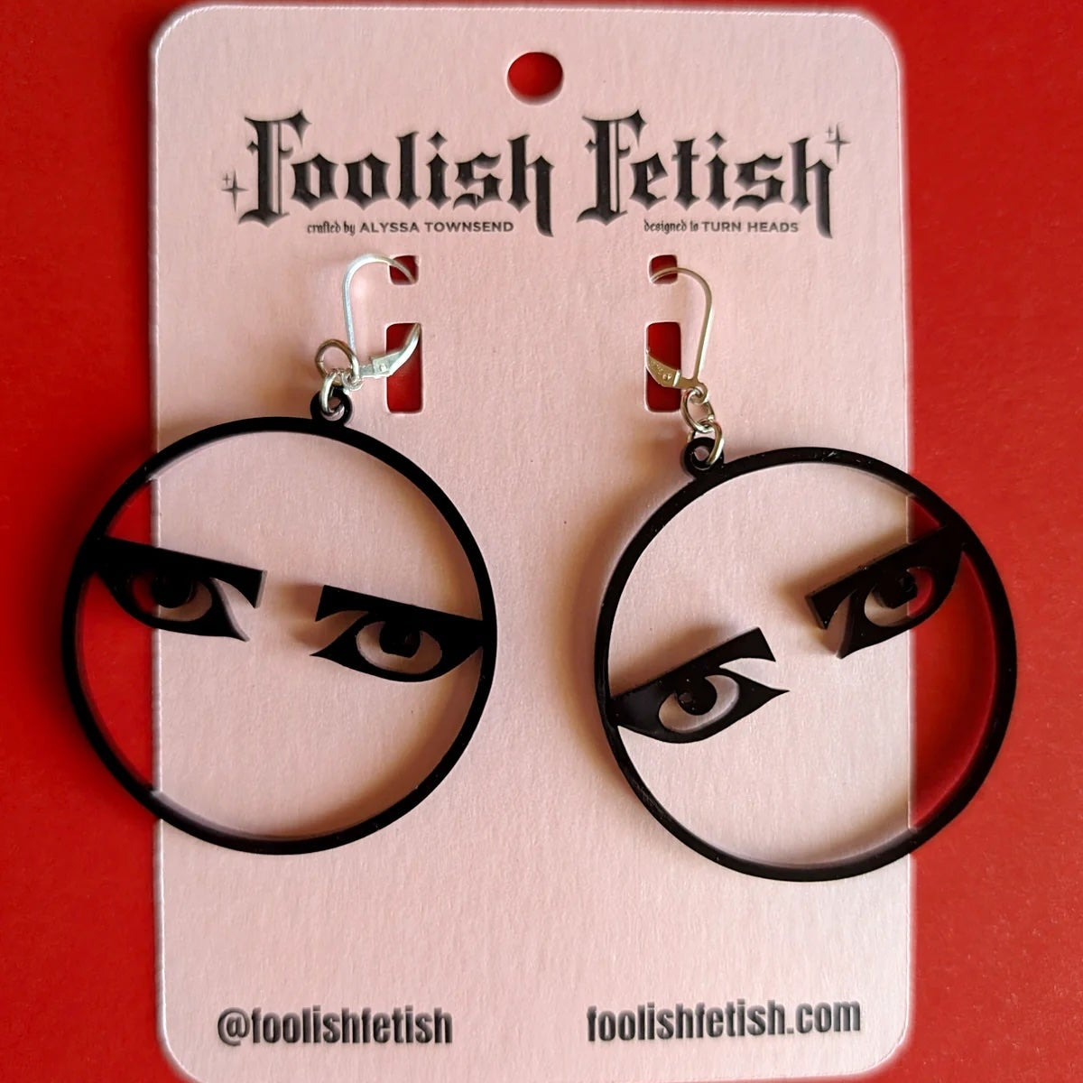 Foolish Fetish earrings on a pink card with a red background