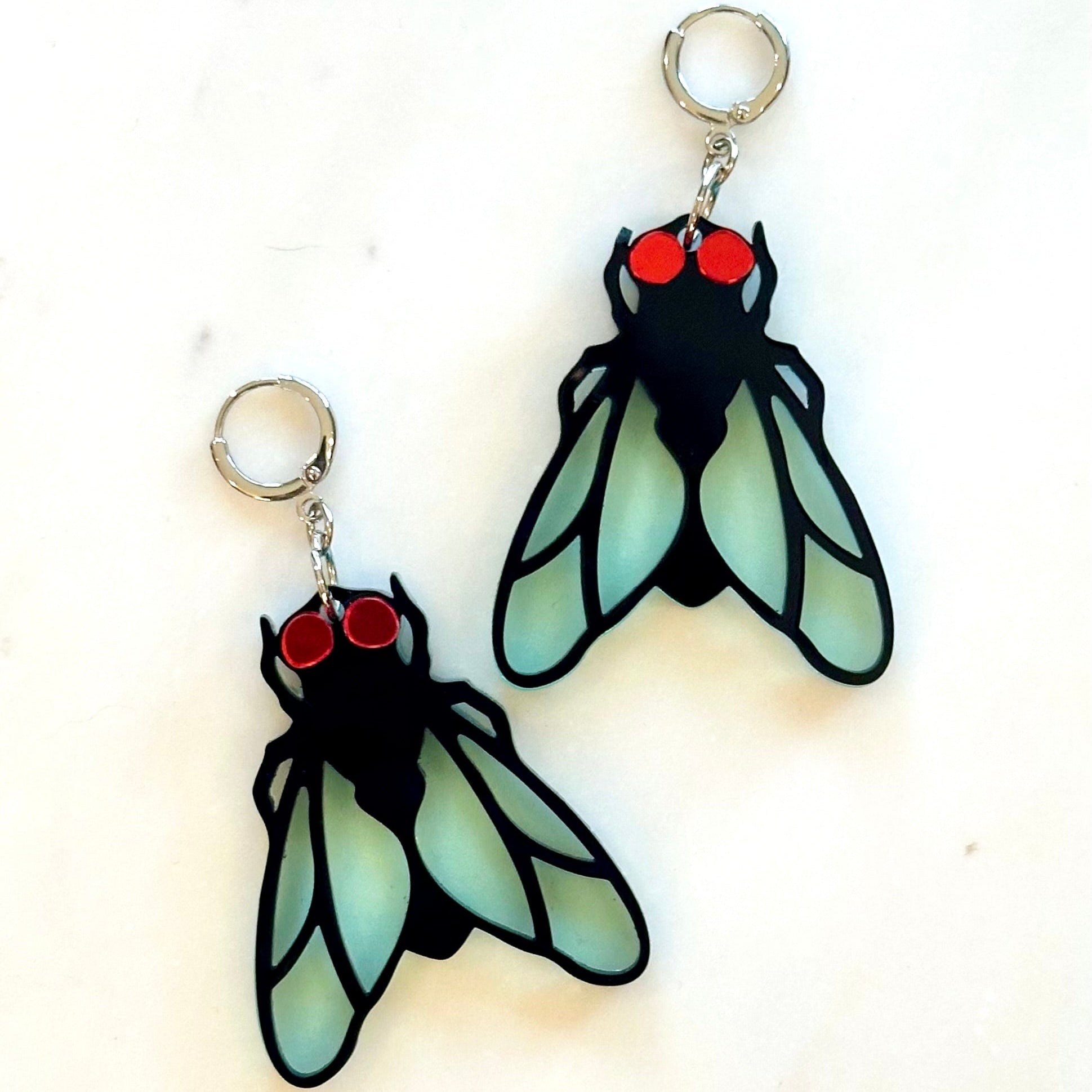 Pair of insect-shaped earrings with red eyes on a white background