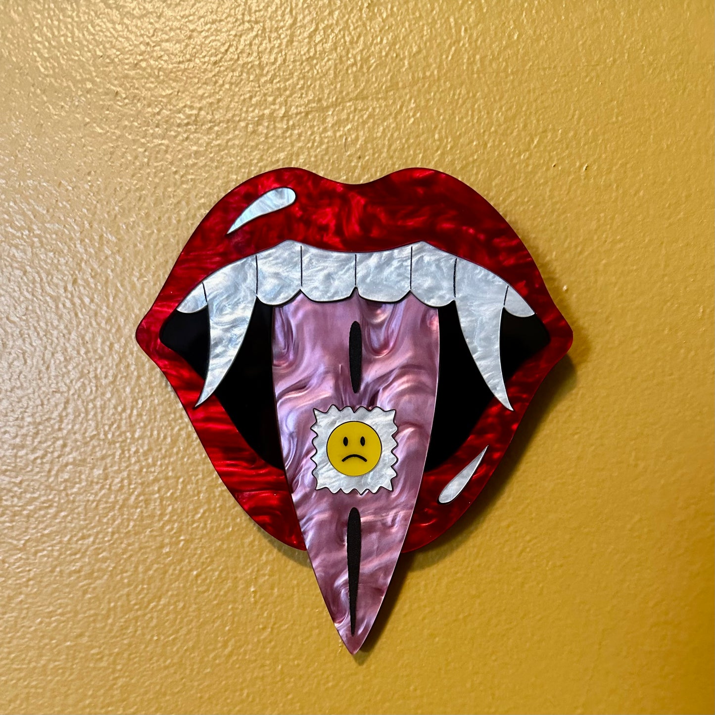 Decorative wall art of a mouth with fangs on a beige background